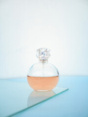 Minimalist composition with women's bottle of perfume on blue background. Floral Fragrance and spring mockup. Perfumery and beauty concept. Front view.