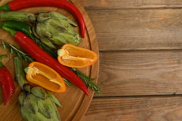 Overhead view of fresh and raw artichoke on the wooden table, vegetable composition bitter pepper, yellow pepper free place for text	
