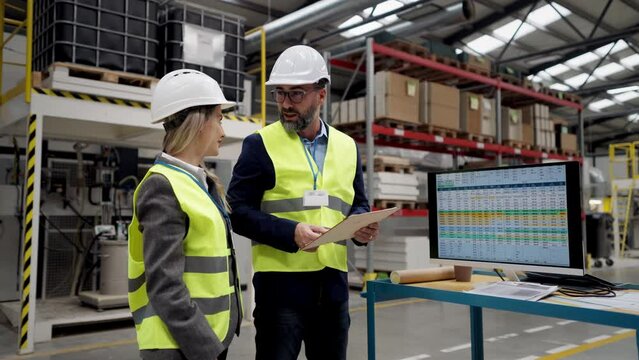 Female engineer and male supervisor standing in modern industrial factory, talking about production. Team management in manufacturing facility