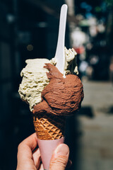 Tasty gelato in waffle cone, pistachio and triple chocolate ice cream scoops. Amazing treat during hot summer in town