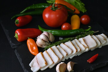 pieces of lard, top view of bacon with red pepper on a black background,	
