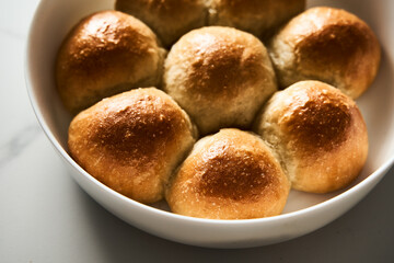 Burger Buns or mini buns in the round baking pan. Very soft Freshly Baked Homemade, buttered. White marble background. Minimalistic photo