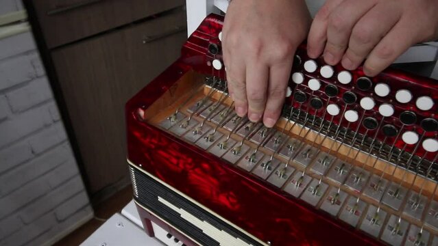 The man checks the compression of the butt button. It presses the valves to the body and spreads the fur. Bayan repair and maintenance.