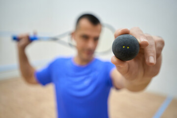 Blurred male squash player hold racquet and ball sportsman having workout