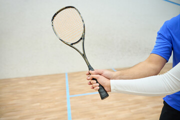 Unrecognizable man teaching woman to properly hold squash racquet