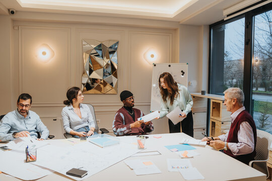 A professional and diverse group of colleagues engaging in a business meeting in a well-lit office. The image depicts teamwork, discussion, and the sharing of ideas among employees.