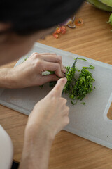 food preparation in kitchen, cutting cilantro leaves with knife on a cutting board, healthy ingredients for food, kitchen utensil