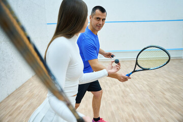 Man athlete engages in squash training learning from experienced instructor