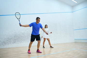 Man coach working with woman focuses on skill development during squash lesson