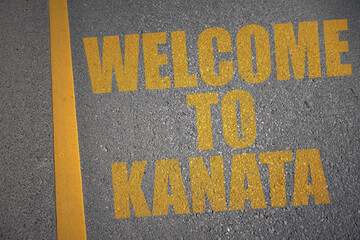 asphalt road with text welcome to Kanata near yellow line.