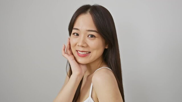 A beautiful young asian woman with long hair smiles gently against a white isolated background.