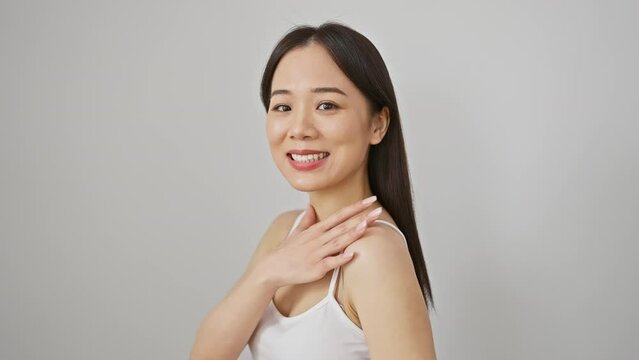 A smiling asian woman in a white tank top poses confidently against a plain white background.