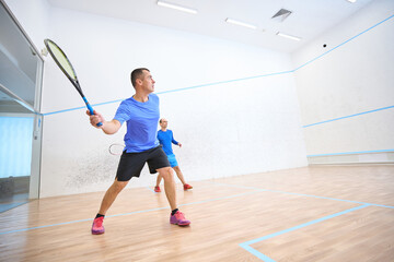 Fit men exercising on squash court promoting healthy lifestyle