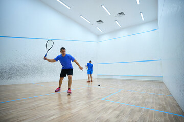 Motivated men engaging in intense squash workout improving their skills