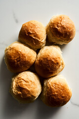 Burger Buns or mini buns on white marble background. Very soft Freshly Baked Homemade, buttered. Minimalistic photo. Top view. 