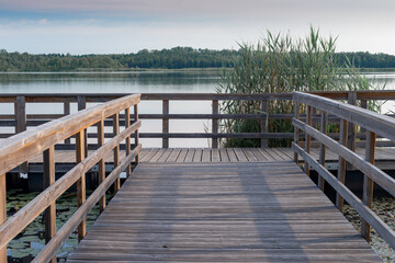 Fototapeta na wymiar piękny drewniany pomost na jeziorze z zalesionymi brzegami