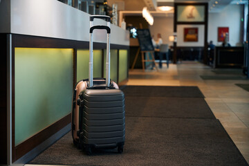 Two suitcases near reception desk in modern hotel lobby with lighting