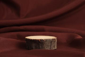 Wooden eco rustic platform podium on brown silk fabric background. Minimal empty display product...