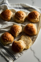 Burger Buns or mini buns on white marble background and kitchen towel. Very soft Freshly Baked Homemade, buttered. Minimalistic photo. 