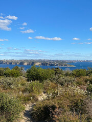 Obraz premium View of the island's coastline from the top of a mountain. Sydney city’s skyscrapers on the horizon. Mountain top with view of the city below.