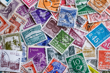 Postage stamps.A collection of world stamps in a pile.Postage stamps from different countries and times - obrazy, fototapety, plakaty