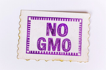 NO GMO. paper tag with text on a white background. a purple stamp impression. label. concept: naturalness, environmental friendliness.