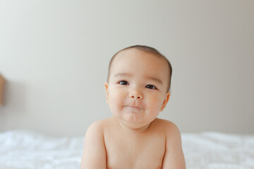 Naked baby sitting on a bed