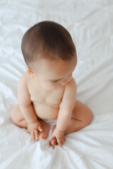 Naked baby sitting on a bed