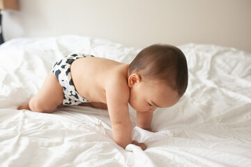 baby laying down on bed topless happily
