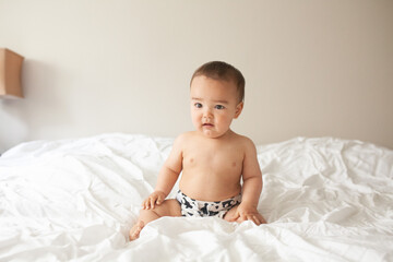 Naked baby sitting on a bed