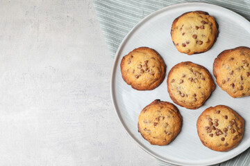 Plate with delicious chocolate chip cookies on gray table, top view. Space for text