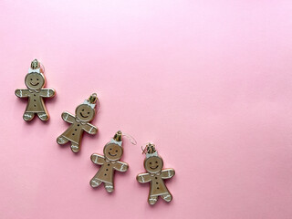 Gingerbread man toys for Christmas tree on pink background. Place for text