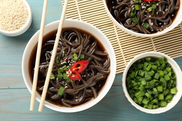 Tasty buckwheat noodle (soba) soup with chili pepper, green onion, sesame and chopsticks on light...