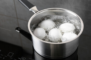 Chicken eggs boiling in saucepan on electric stove