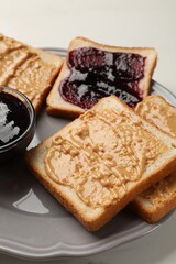 Delicious toasts with peanut butter and jam on table, closeup