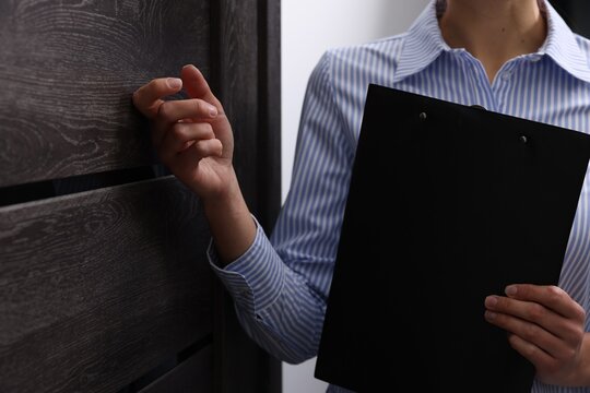Collector with clipboard knocking on door indoors, closeup