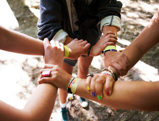 People, hands together and outdoor festival with arm bands for community, teamwork or unity at...
