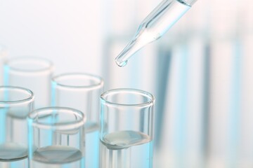Laboratory analysis. Dripping liquid from pipette into glass test tube on blurred background,...