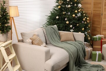Sofa near Christmas tree in room. Festive interior design