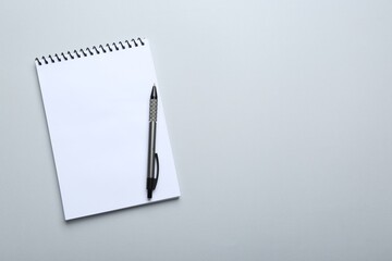 One notebook and pen on light grey background, top view. Space for text