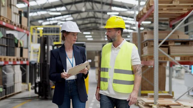 Female warehouse director talking with production manager, discussing new order, preparing products for shipmennt, delivery, checking stock in warehouse.