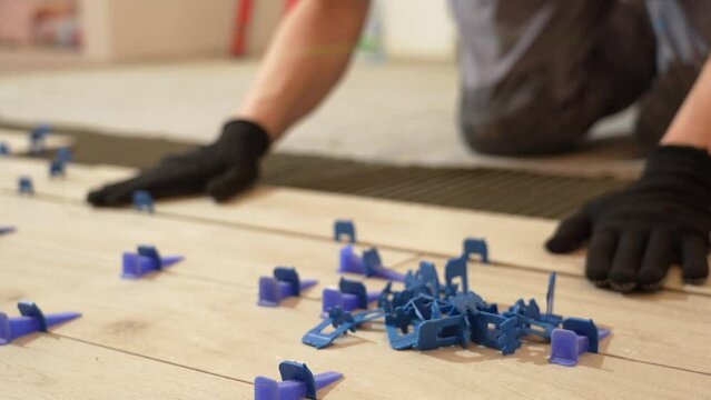 A tiler lays floor tiles on the floor. Porcelain tiles in the kitchen. A tiler is gluing tiles to the kitchen floor. A man is laying tiles on the bathroom floor.