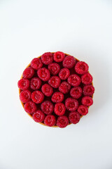 French dessert. Tart with raspberries with almond frangipane and raspberry coulis inside. Decorated with fresh raspberries. White background. Top view.