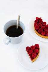Slice of a raspberry tart with a cup of black coffee