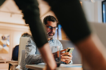 The businessman uses his break wisely, checking his phone for updates and messages.