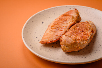 Delicious fresh grilled chicken fillet with spices and herbs on a dark concrete background