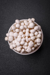 Small white edible beech mushrooms with salt and spices on a plain background