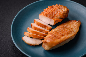 Delicious fresh grilled chicken fillet with spices and herbs on a dark concrete background