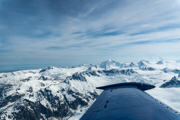 Beechcraft Bonanza airplane wingtip flies over Lake Clark Pass in Alaska. Mount Redoubt in the...