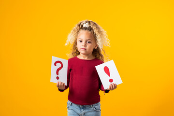 Enchanting Exploration. A Portrait of a Thoughtful child Girl Holding Cards with Question Marks and...